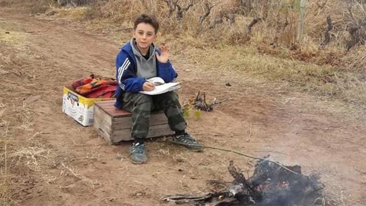 Cumple sus tareas virtuales junto a su padre en medio de la finca y al lado de una fogata